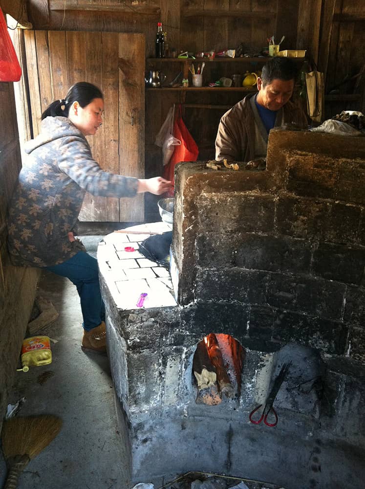 A photo of Sami cooking on a wood burning cement block stove in her childhood home