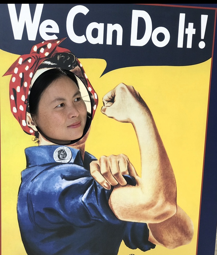 A photo of Sami posing in a We Can Do It sign